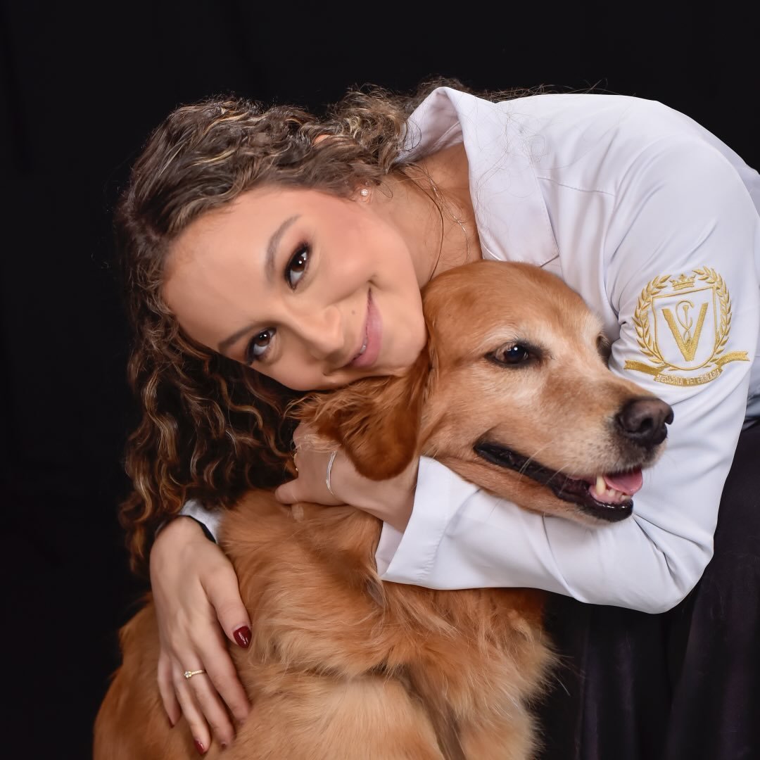 Dra. Clara Viana abraçando um golden retriever, vestindo jaleco branco